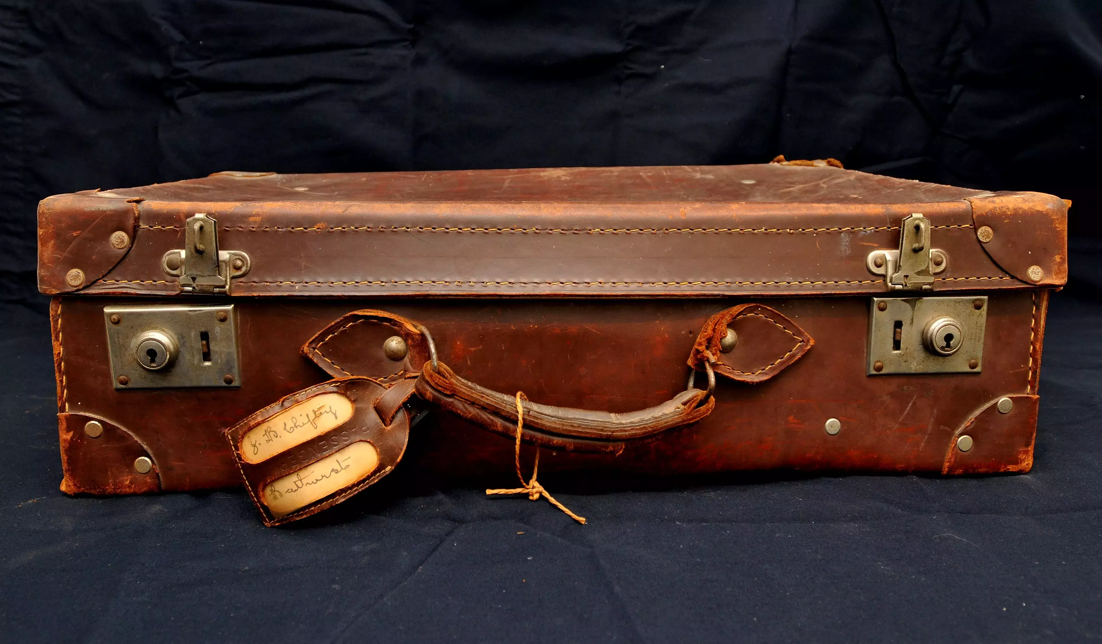 A brown leather suitcase with a tag.  